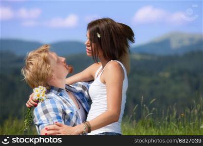Happy beautiful couple in love on the green grass meadow