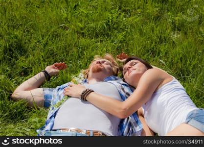 Happy beautiful couple in love sleeping on the green grass field