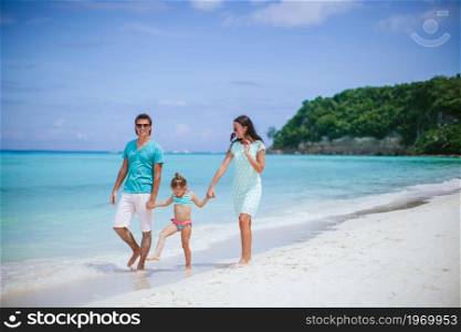 Happy beautiful family of three on the beach. Young family on white beach during summer vacation