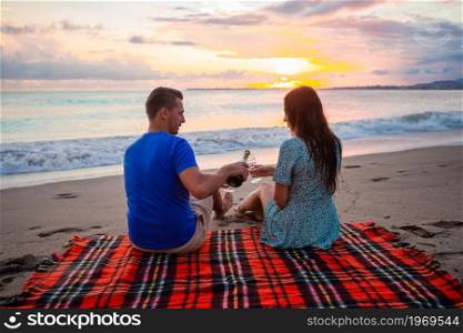Happy beautiful family on a tropical beach having picnic together on the sunset. Family having a picnic on the beach