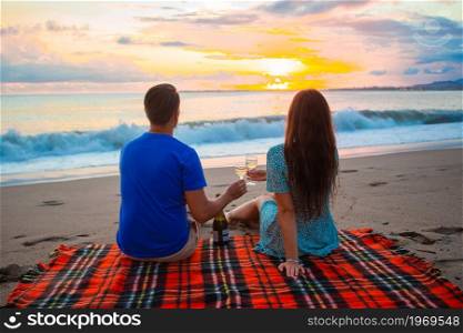 Happy beautiful family on a tropical beach having picnic together on the sunset. Family having a picnic on the beach