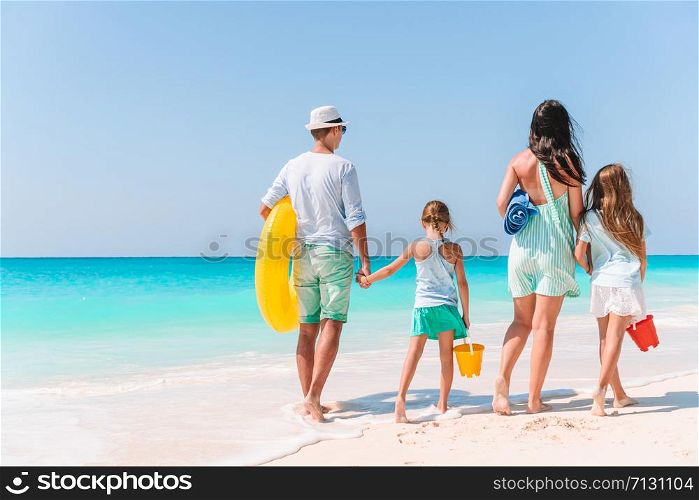 Happy beautiful family on white beach. Back view.. Happy beautiful family of four on white beach