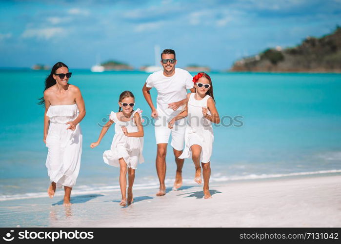 Happy beautiful family on white beach having fun. Young family of four on vacation have fun