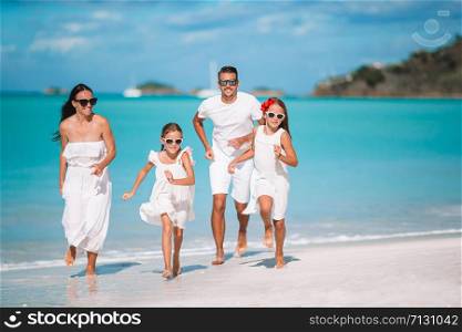 Happy beautiful family on white beach having fun. Young family of four on vacation have fun