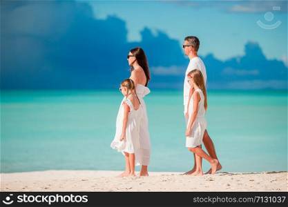 Happy beautiful family on white beach walking together. Happy beautiful family of four on white beach