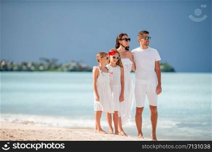 Happy beautiful family on white beach walking together. Happy beautiful family of four on white beach