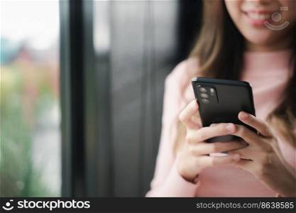 Happy beautiful female typing text message on smart phone device and enjoyment lifestyle with social networking media, Asian young woman using mobile phone at cafe coffee shop to shopping online