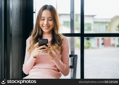 Happy beautiful female typing text message on smart phone device and enjoyment lifestyle with social networking media, Asian young woman using mobile phone at cafe coffee shop to shopping online