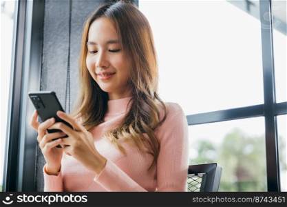 Happy beautiful female typing text message on smart phone device and enjoyment lifestyle with social networking media, Asian young woman using mobile phone at cafe coffee shop to shopping online