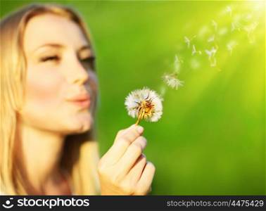 Happy beautiful girl blowing dandelion, over green nature background, selective focus, wish concept