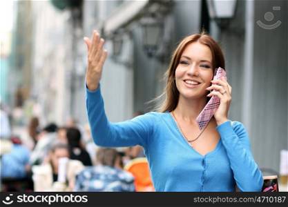 Happy beautiful girl calling by phone in a summer street