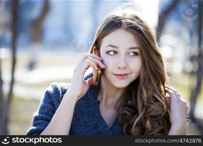 Happy beautiful girl calling by phone in spring park