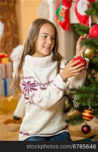 Happy beautiful girl decorating Christmas tree at living room