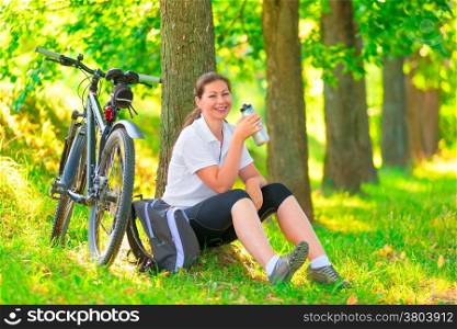 happy beautiful girl has a rest sitting in a tree with a bicycle