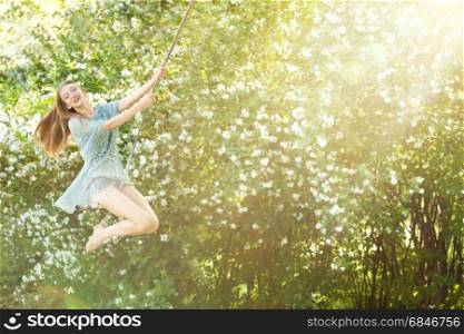 Happy. Beautiful girl swinging in the park on a swing. In the sun rays. Happy. Beautiful girl swinging in the park on a swing. In the su