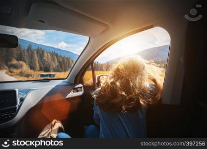Happy beautiful girl traveling in a car across at the mountains Dolomites, Italy. Europe