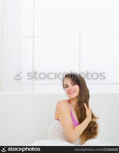 Happy beautiful long hair woman sitting in bed