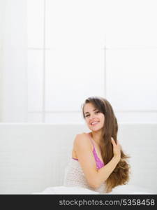 Happy beautiful long hair woman sitting in bed