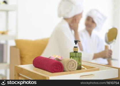 Happy beautiful mom and daughter in white bathrobe applying moisturizing cream on face at home, skin care and treatment concept  