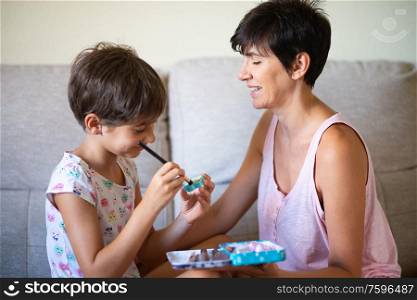 Happy beautiful mother and her little cute daughter doing make up for each other. Mum spending free time with her daughter.. Mother and her little daughter doing make up for each other