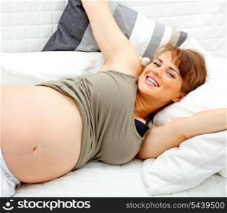 Happy beautiful pregnant female relaxing on sofa at home.&#xA;