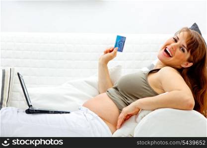 Happy beautiful pregnant woman using credit card to shop from net&#xA;
