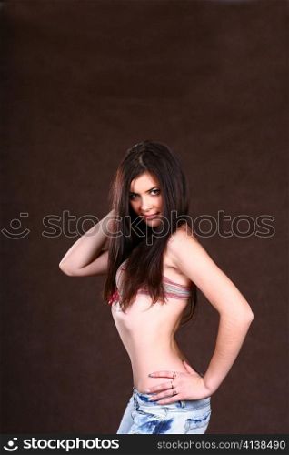 Happy beautiful sexy young woman in top of bikini and jeans on brown background