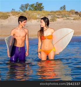 Happy beautiful teenager surfer couple on the beach shore