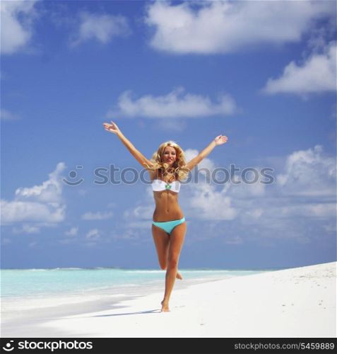 Happy beautiful woman in bikini running on the beach