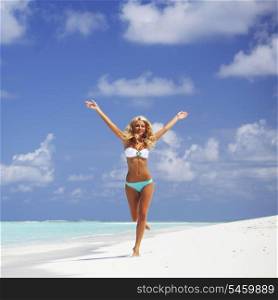 Happy beautiful woman in bikini running on the beach