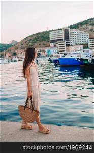 Happy beautiful woman in the port walking on the ships background. Summer vacation . Young beautiful woman walking on dock near the boat