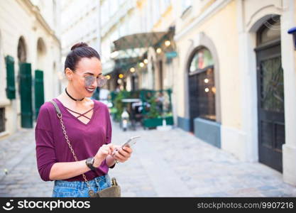 Happy beautiful woman outdoors in the city. Woman talk by her smartphone in city. Young attractive tourist outdoors in italian city