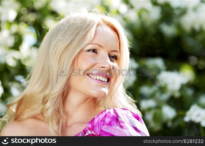 Happy beautiful woman over flowers background outdoors