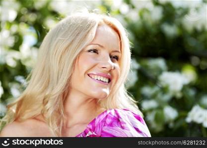 Happy beautiful woman over flowers background outdoors