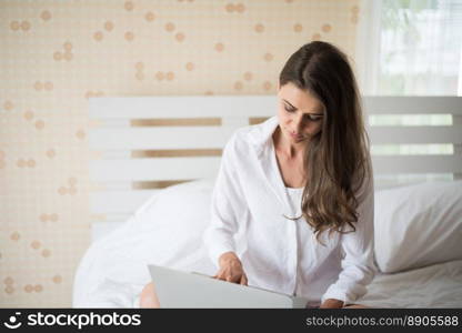 Happy Beautiful woman working on a laptop on the bed in the house