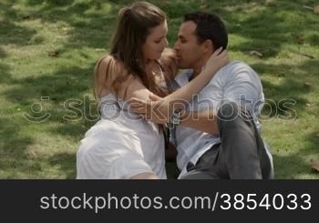 Happy beautiful young man and woman in love, lying on grass in park. Slow motion
