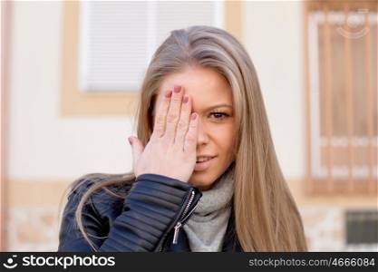 Happy beautiful young woman covering her eye at street