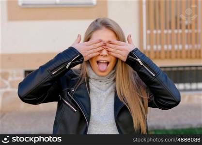 Happy beautiful young woman covering her eyes at street