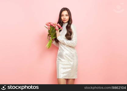 Happy beauty woman with pink tulip bouquet on light pink background. 8th of March celebration