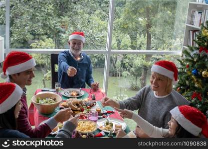 happy big family party and play sparkle fire to celebrate on christmas dinner in dining room that decorated with christmas tree for christmas festival day, happy family holiday concept