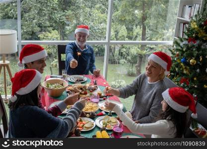 happy big family party and play sparkle fire to celebrate on christmas dinner in dining room that decorated with christmas tree for christmas festival day, happy family holiday concept