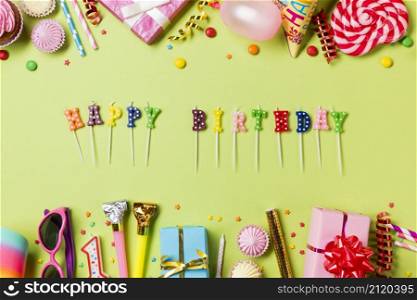 happy birthday candles with colorful birthday items green backdrop