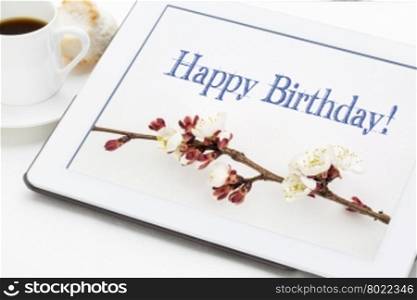 Happy Birthday greeting card - handwriting with apricot tree flowers on digital tablet with a cup of coffee