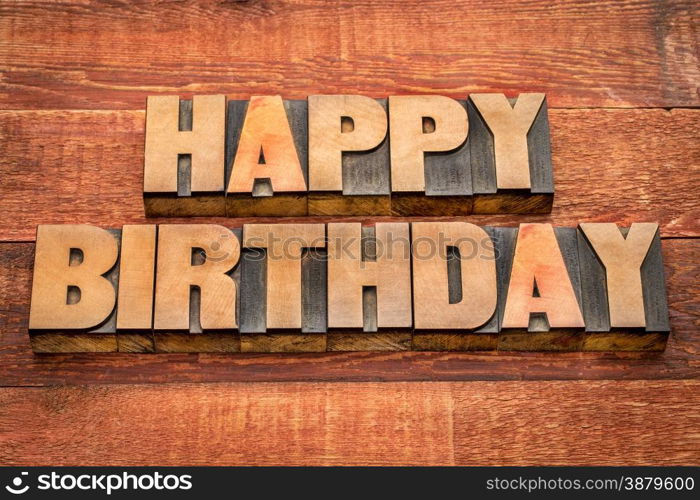 Happy Birthday greetings in letterpress wood type against rustic, red painted barn wood