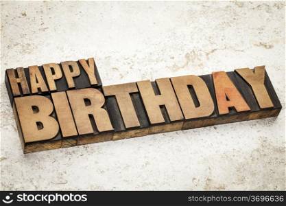 happy birthday text in vintage letterpress wood type on a ceramic tile background