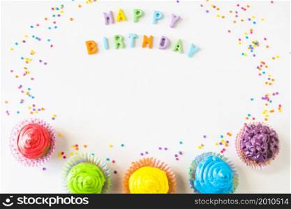 happy birthday text with colorful muffins white backdrop