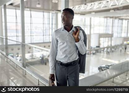 Happy black businessman with briefcase in car dealership. Successful business person on motor show, black man in formal wear, automobile showroom. Black businessman with briefcase in car dealership