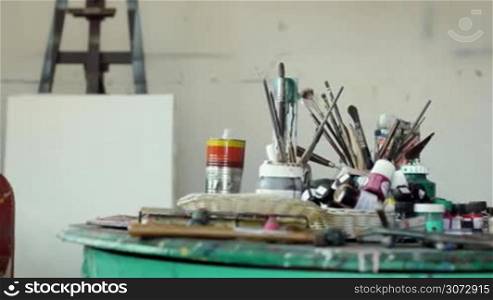 Happy black people painting for hobby. Portrait of confident african american man at work as professional painter, skilled artist in art studio, looking at camera, smiling near table full of equipment