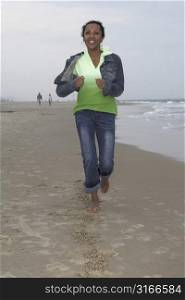 Happy black woman running along the shoreline