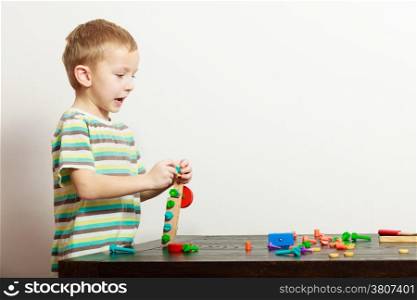 Happy blond boy child kid preschooler playing with colorful building blocks toys interior. At home. Childhood.
